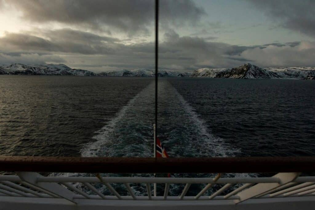 Couple viewing Norwegian fjord cliffs from luxury cruise balcony
