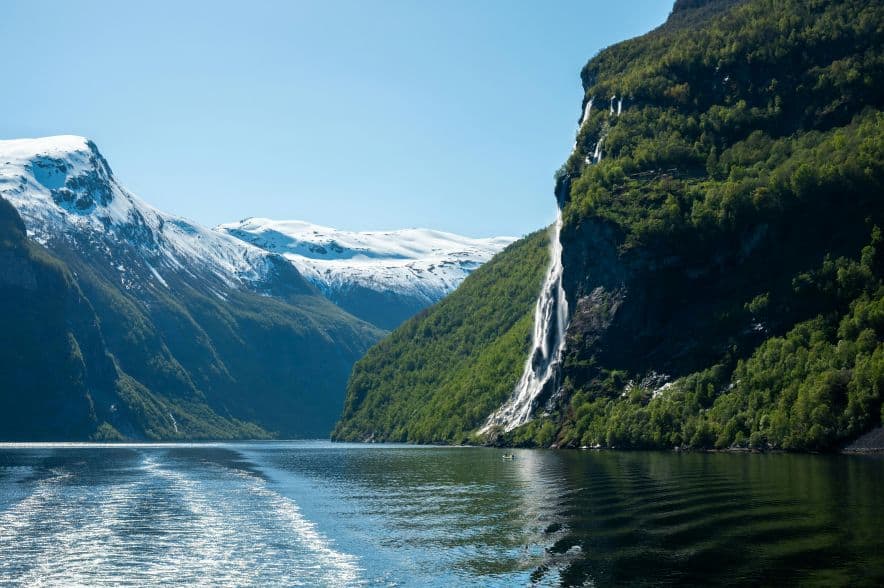 Waterfall flowing into a Norwegian fjord during spring travel season