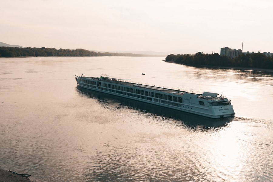A Danube river cruise ship docked near Budapest with Parliament visible in the background.